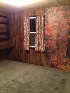 Bedroom 2 with wood paneling, forest wallpaper and wood shelving